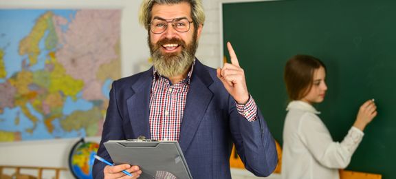 Happy teacher and girl writing on the blackboard