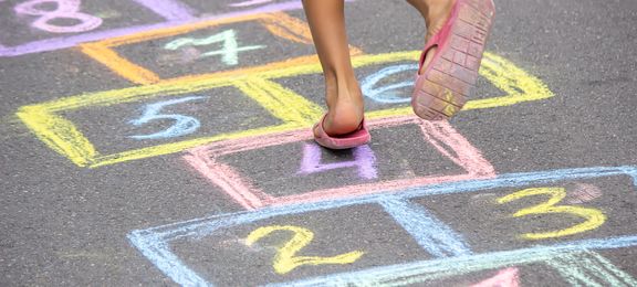 Little girl playing hopscotch outside