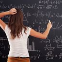 Young woman looking at precalculus math problem on blackboard