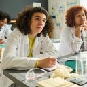 Щасливий підліток у лабораторному халаті, що дивиться на вчителя природничих наук