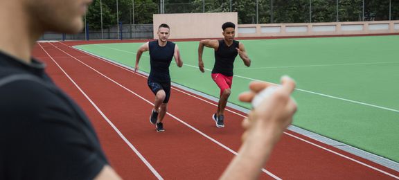 Man timetracking two runners with a stopwatch