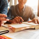 Two people reading in a book and taking notes