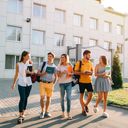 Fem studenter går rundt med bøker på campus på universitetet