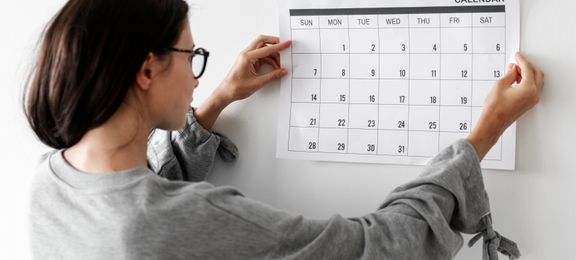 Woman holding up a calendar, ready to plan her month
