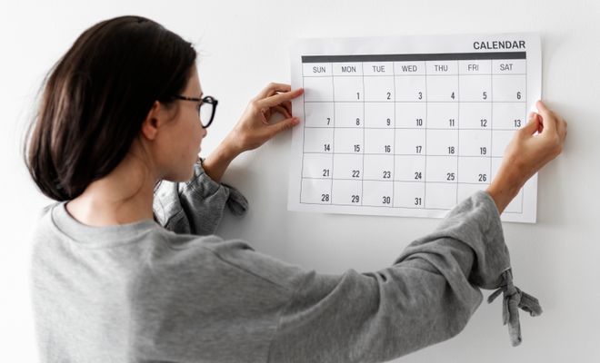 Woman holding up a calendar, ready to plan her month